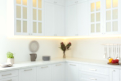 Photo of Blurred view of modern kitchen interior with white furniture