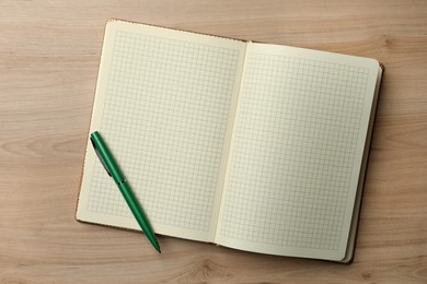 Photo of Open notebook and pen on wooden table, top view. Personal planning