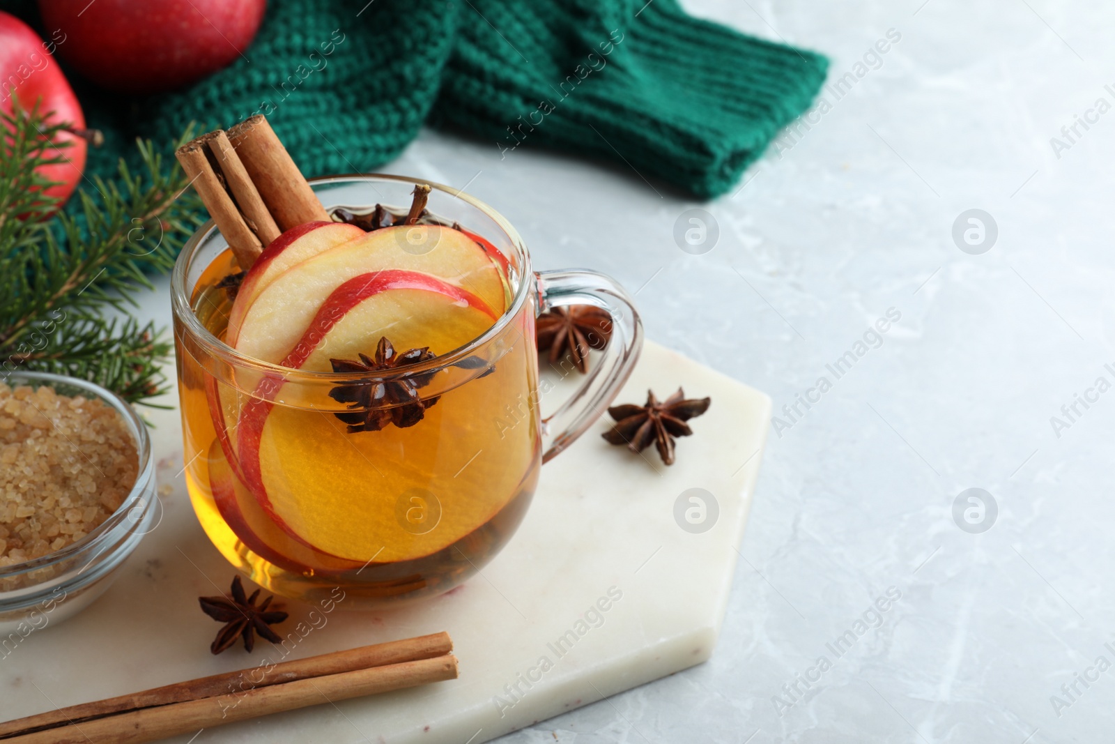 Photo of Aromatic hot mulled cider on light grey marble table. Space for text