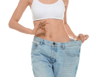 Photo of Slim young woman with smooth gentle skin in oversized jeans on white background, closeup. Beauty and body care concept