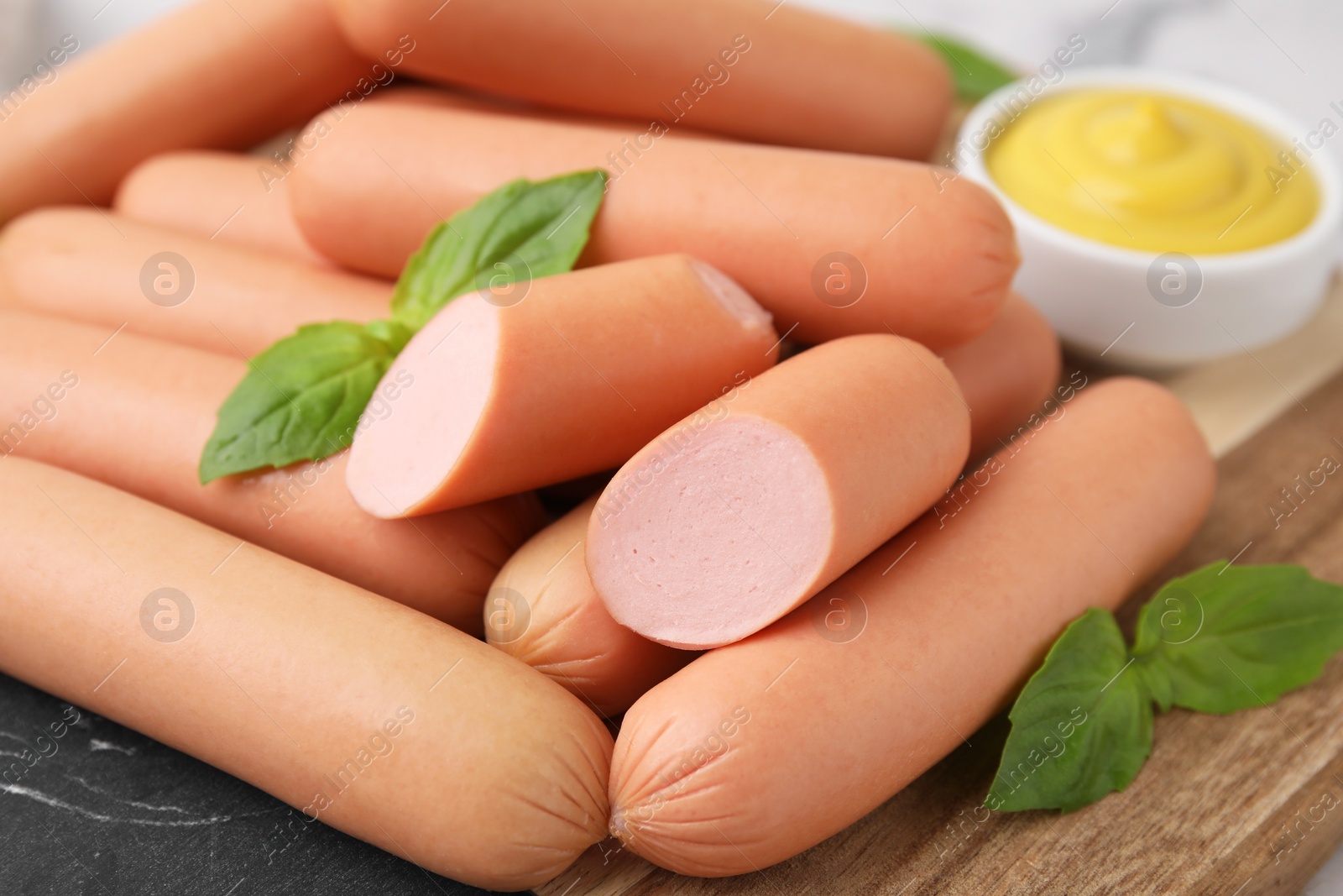 Photo of Delicious boiled sausages and basil on table, closeup