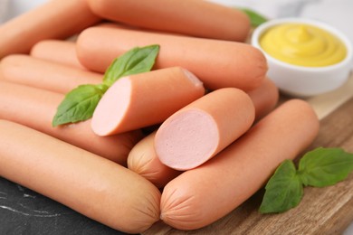 Photo of Delicious boiled sausages and basil on table, closeup