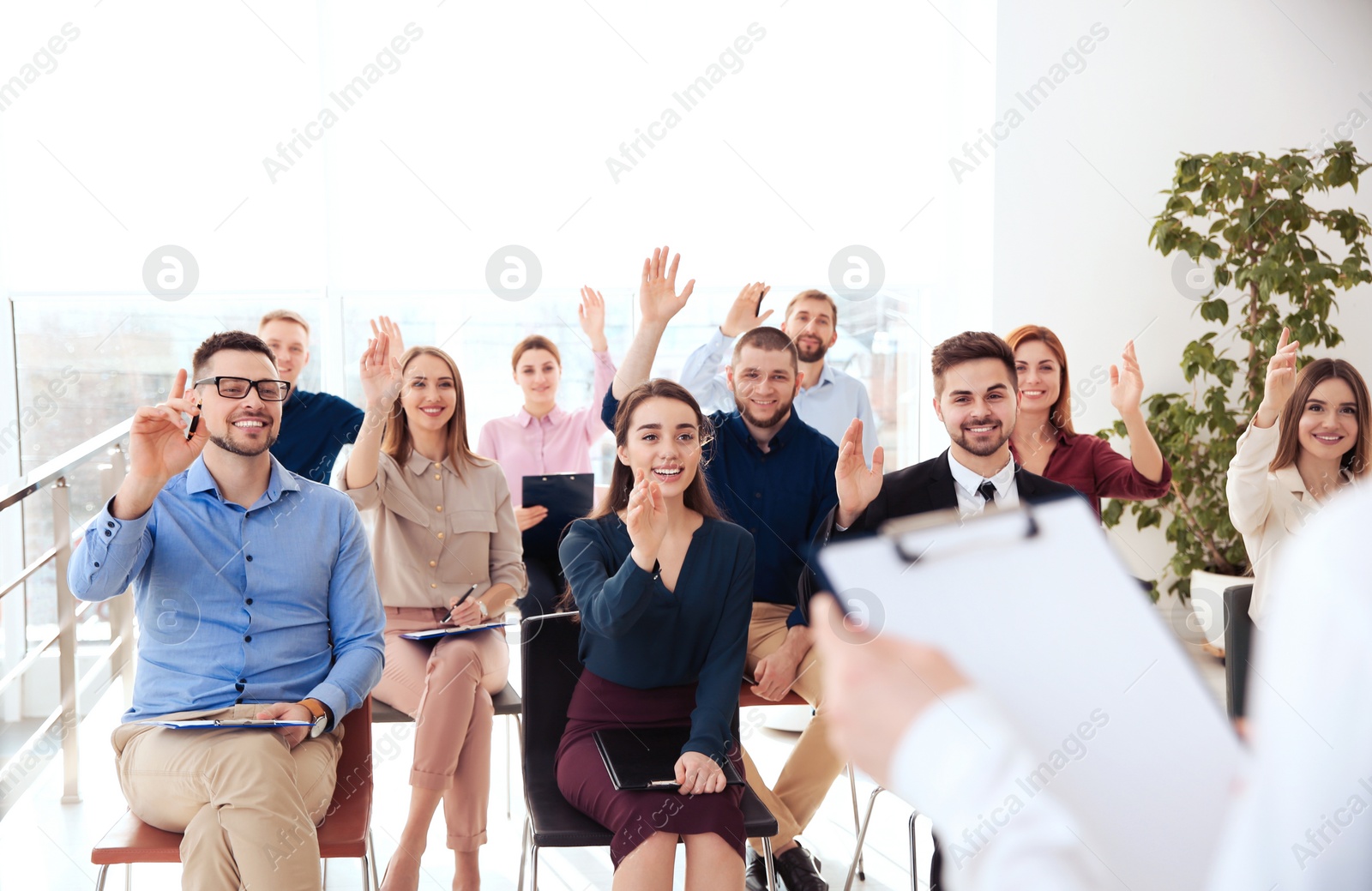 Photo of People raising hands to ask questions at business training indoors