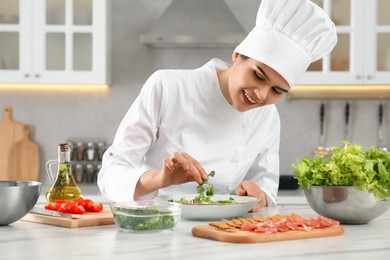 Photo of Professional chef cooking delicious salad at white marble table in kitchen