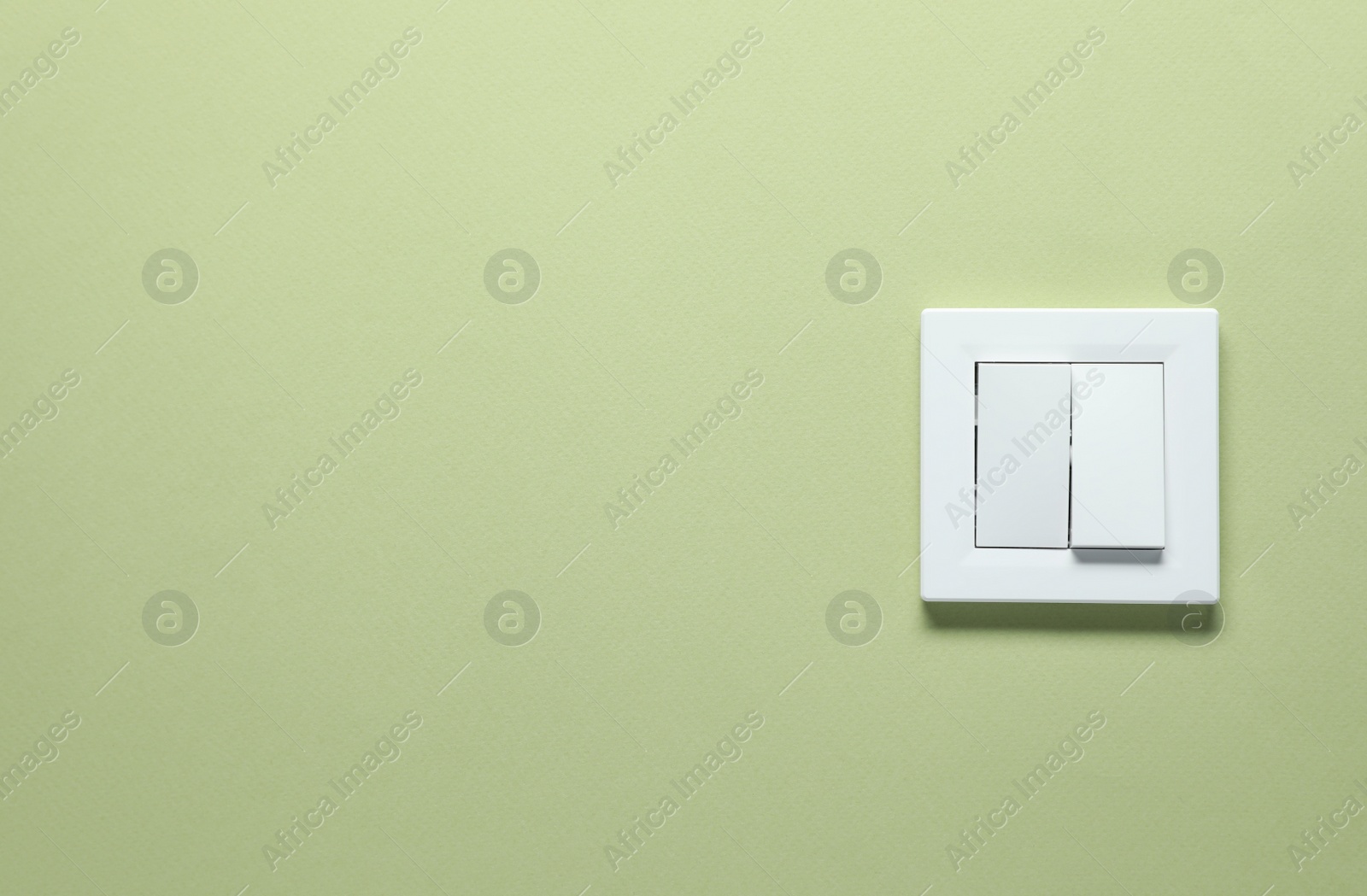 Photo of Modern plastic light switch on green background. Space for text