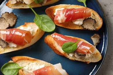 Photo of Delicious bruschettas with cheese, prosciutto and slices of black truffle on grey table, top view