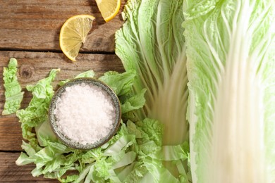 Photo of Fresh Chinese cabbage, salt and lemon on wooden table, flat lay