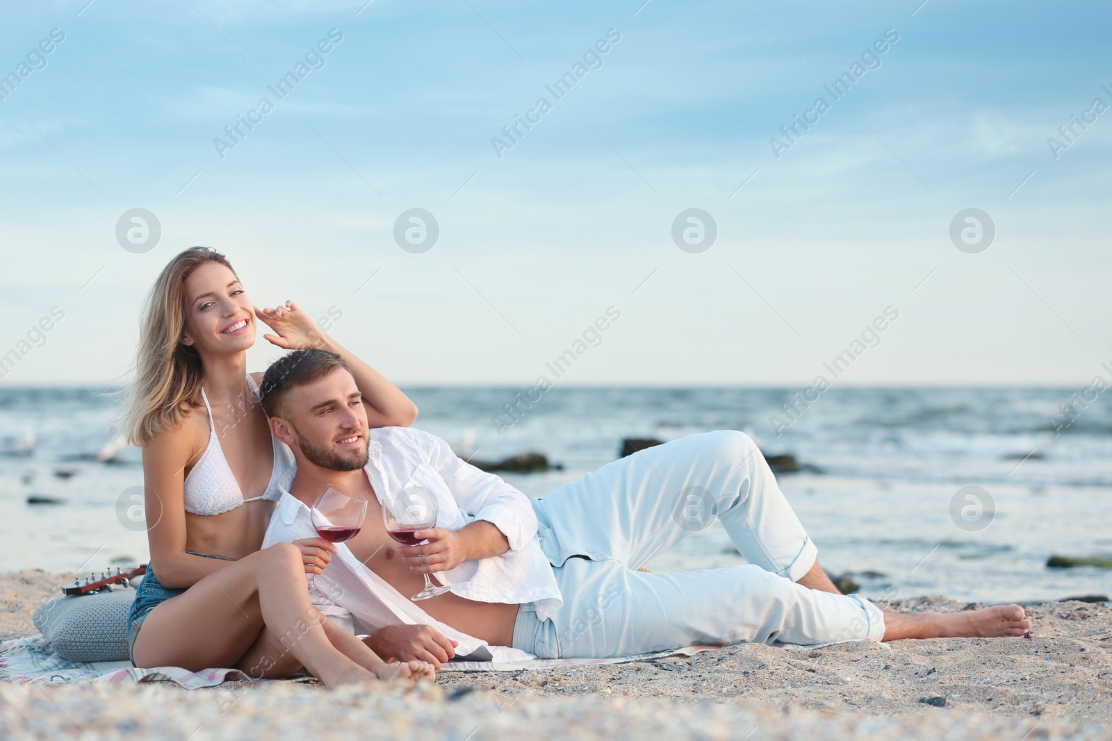 Photo of Young couple with glasses of wine on beach