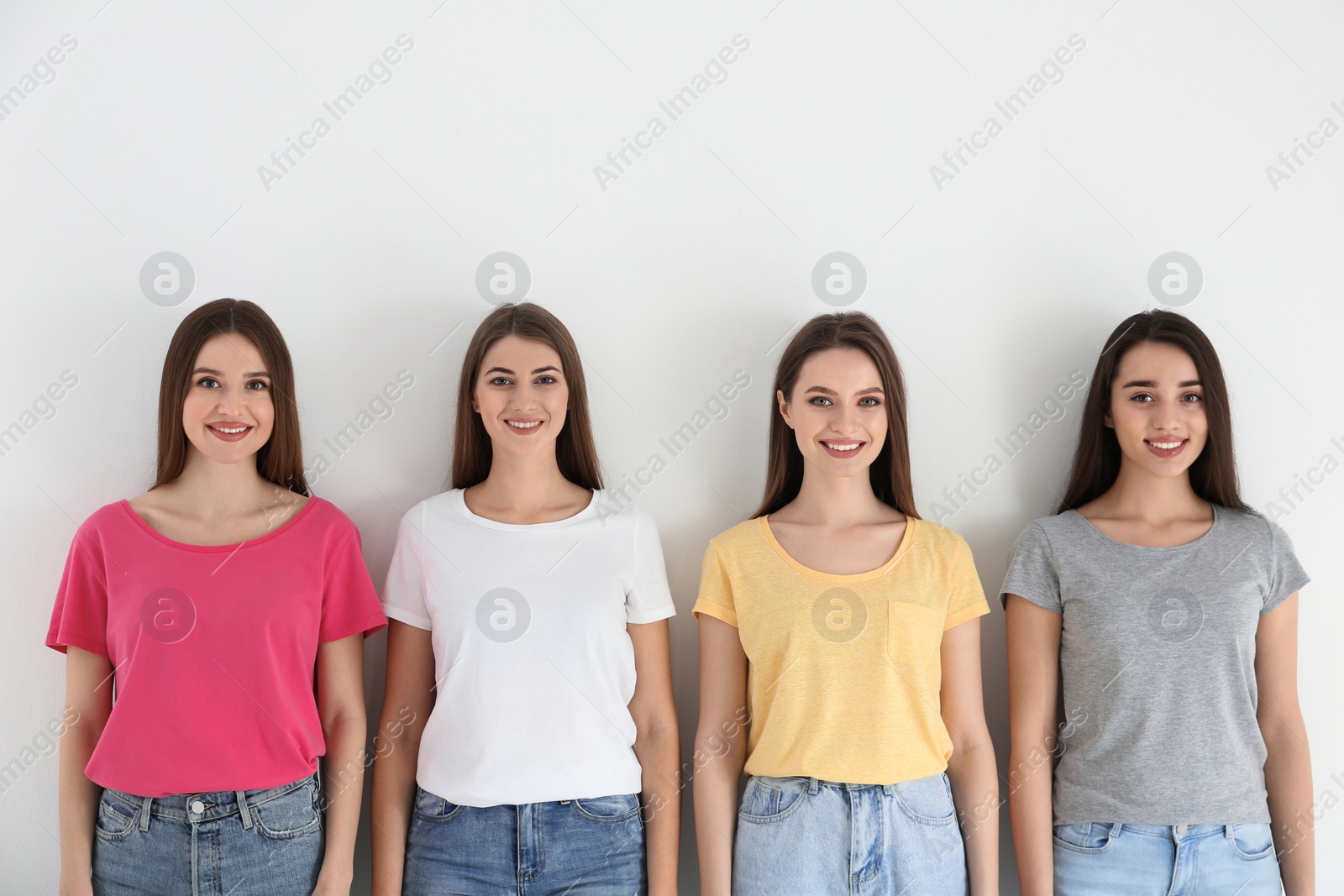 Photo of Beautiful young ladies in jeans and colorful t-shirts on white background. Woman's Day