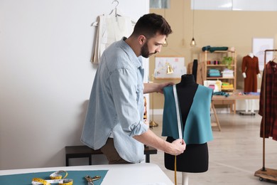 Dressmaker with measuring tape working in atelier