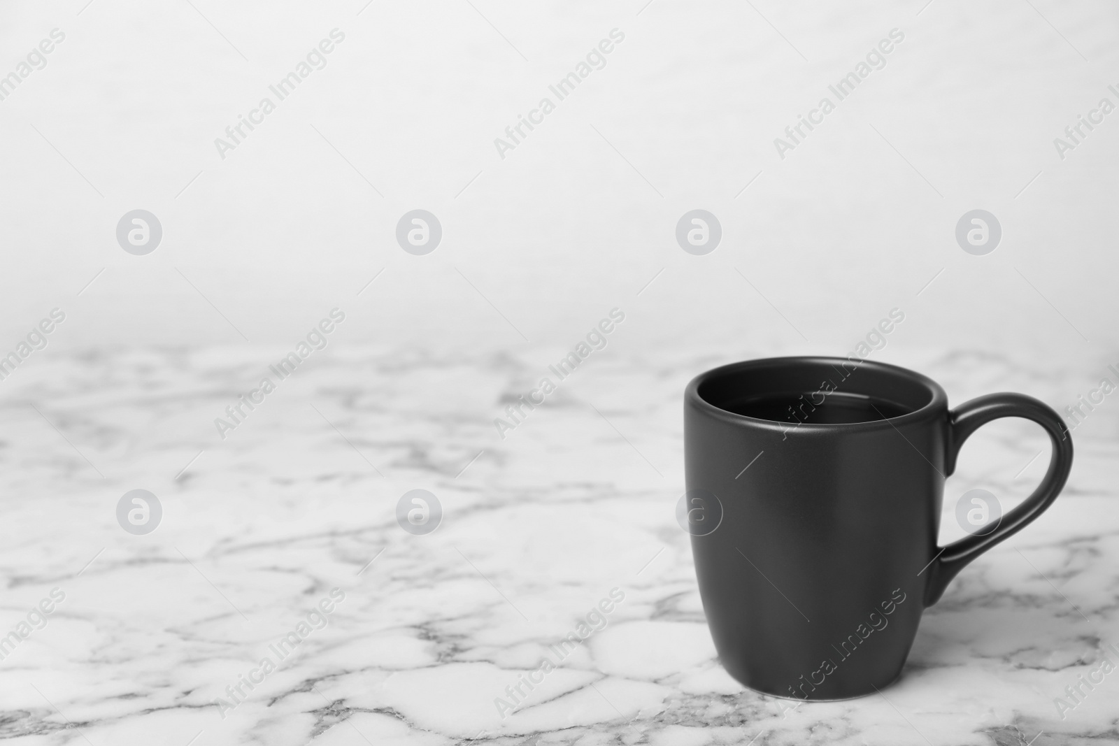 Photo of Black ceramic cup with hot aromatic coffee on table