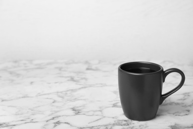 Black ceramic cup with hot aromatic coffee on table