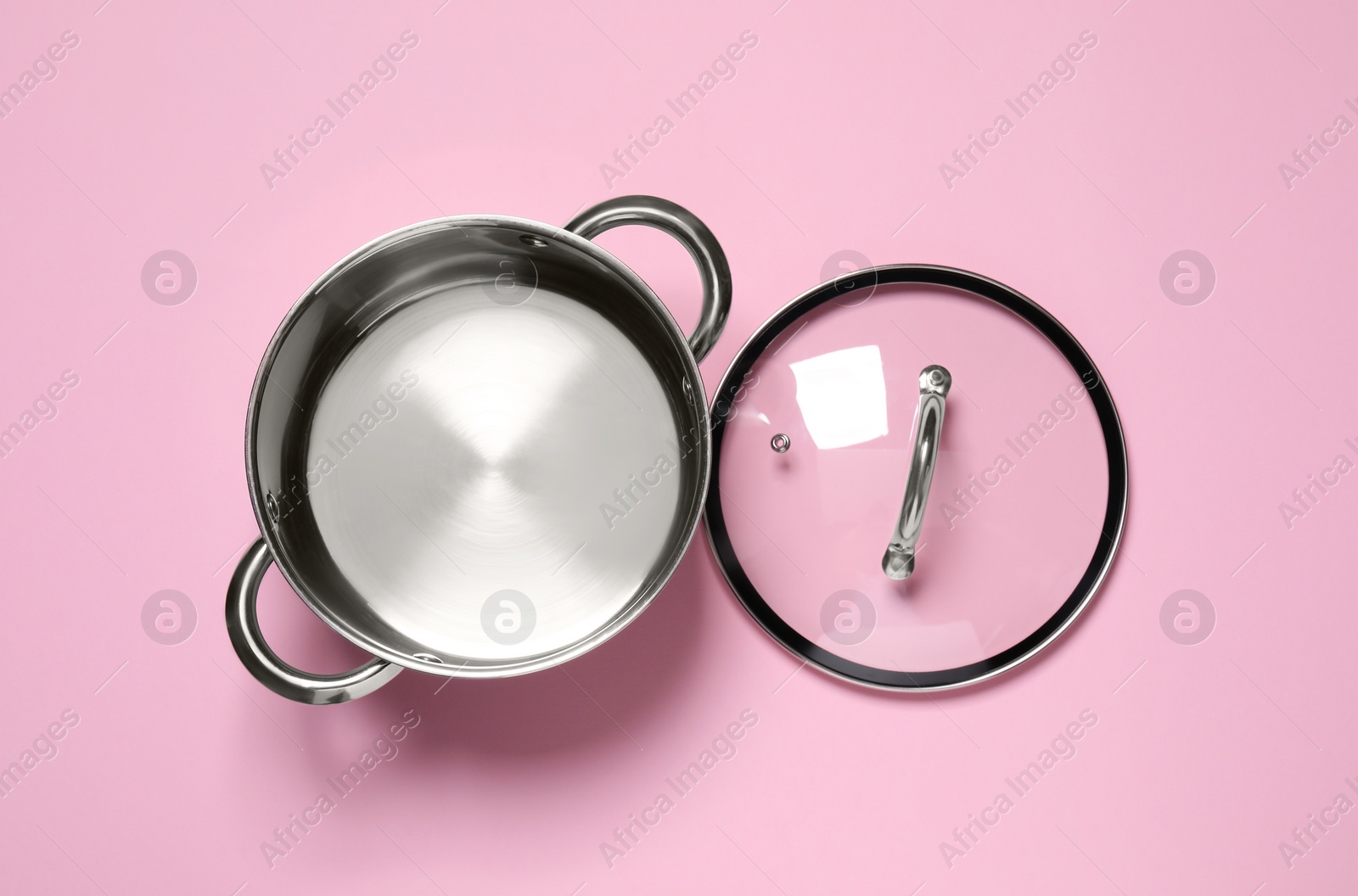 Photo of Steel pot and glass lid on pink background, flat lay