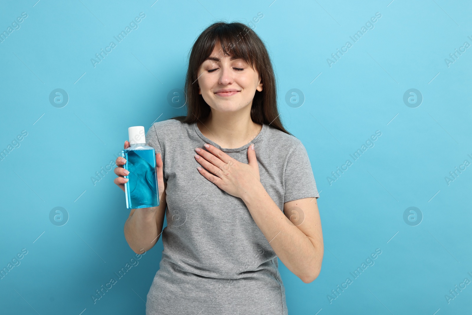 Photo of Young woman with mouthwash on light blue background