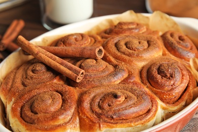 Photo of Baking dish with cinnamon rolls on table, closeup