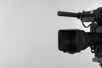 Photo of Modern professional video camera on light background. Space for text