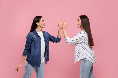 Photo of Women giving high five on pink background