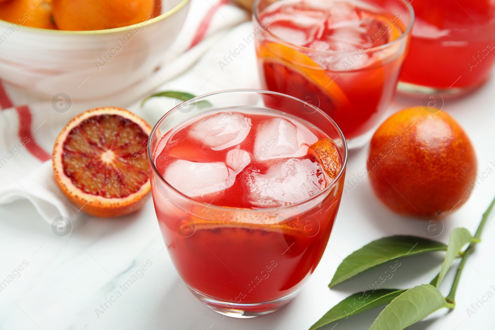 Photo of Tasty sicilian orange juice with ice cubes and fruits on white marble table