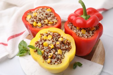 Photo of Quinoa stuffed bell peppers and basil on white table, closeup