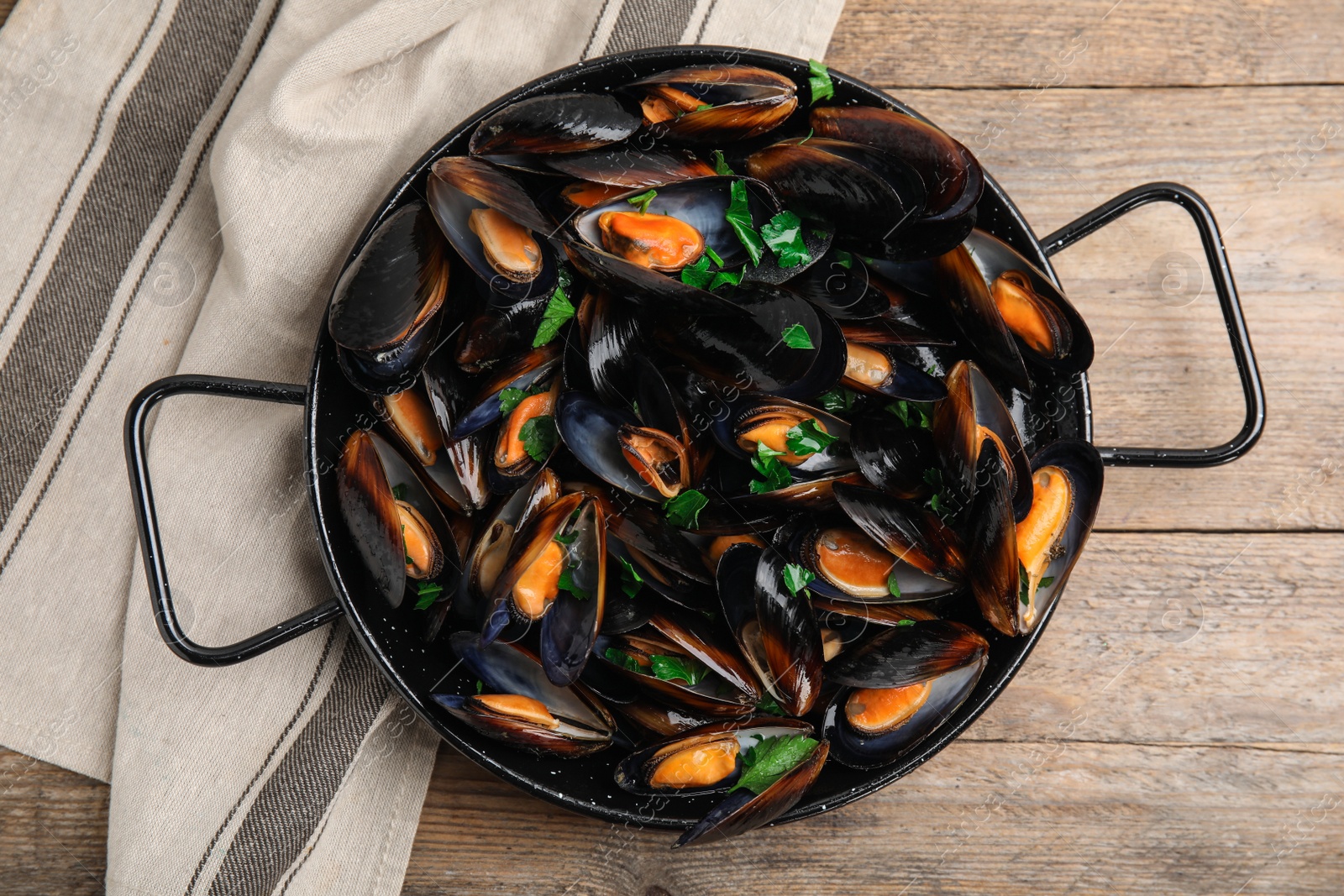 Photo of Pan of cooked mussels with parsley on wooden table, top view