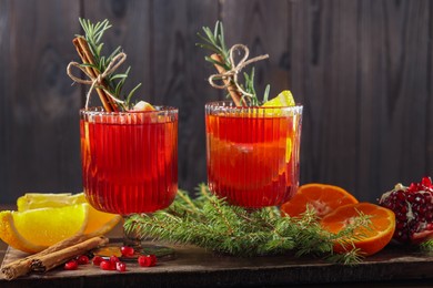 Photo of Christmas Sangria cocktail in glasses, ingredients and fir tree branches on table