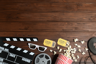 Photo of Flat lay composition with clapperboard, cinema tickets and 3d glasses on wooden table, space for text