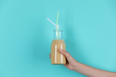 Young woman holding bottle of healthy smoothie on color background