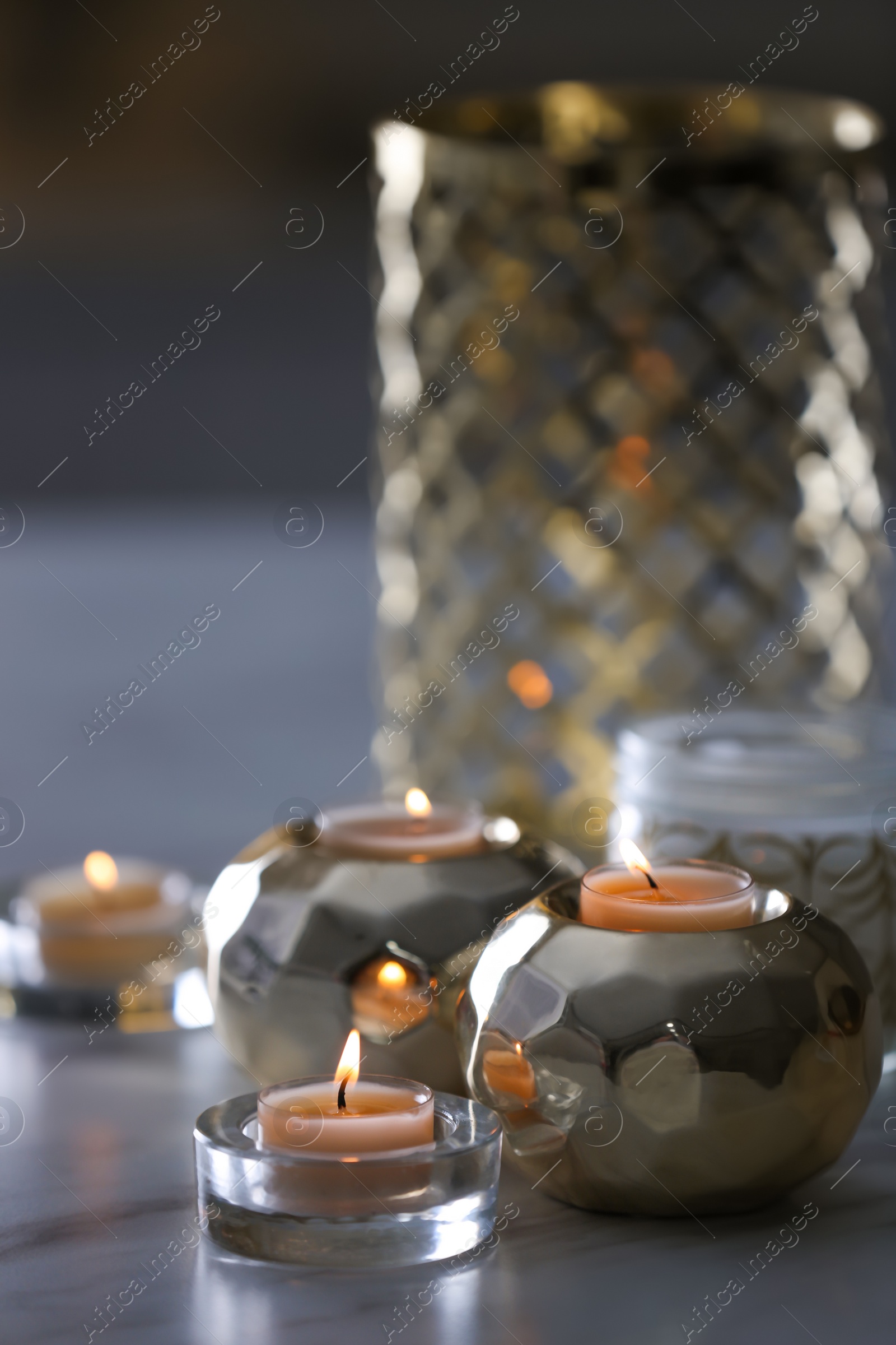 Photo of Burning candles in holders on white marble table indoors