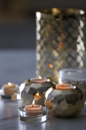 Photo of Burning candles in holders on white marble table indoors