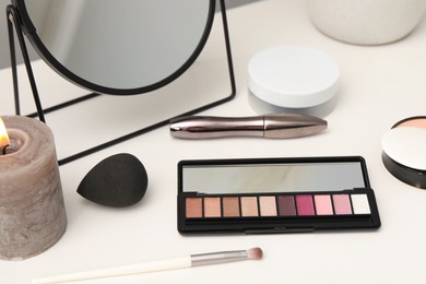 Photo of Mirror, cosmetic products and burning candle on dressing table