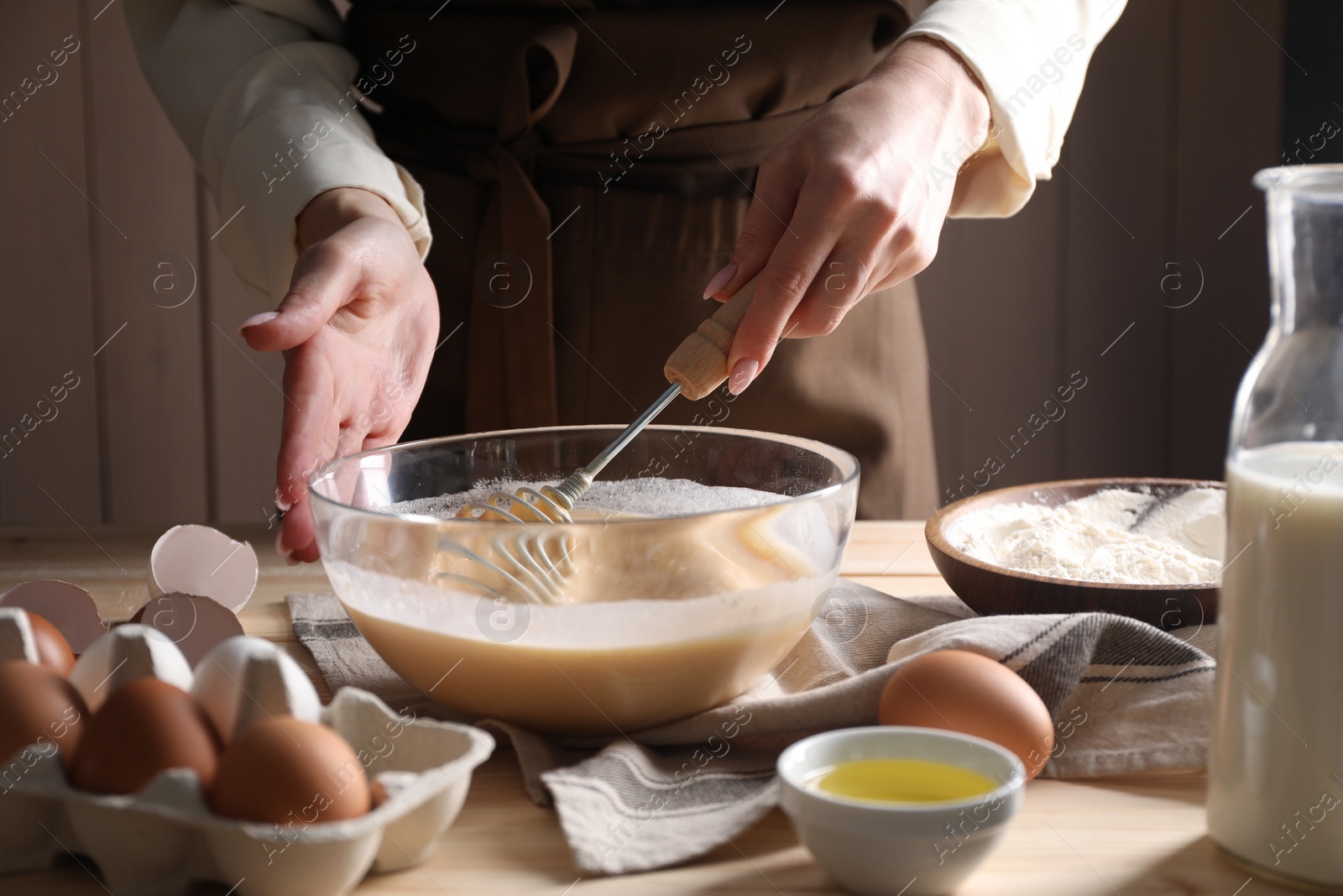 Photo of Woman making dough with whisk in bowl at table, closeup