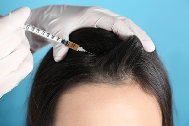 Photo of Young woman with hair loss problem receiving injection on color background, closeup