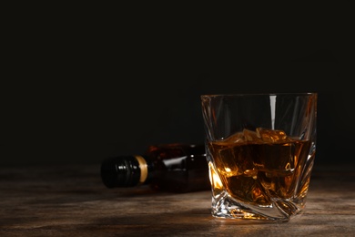 Golden whiskey in glass with ice cubes on table. Space for text