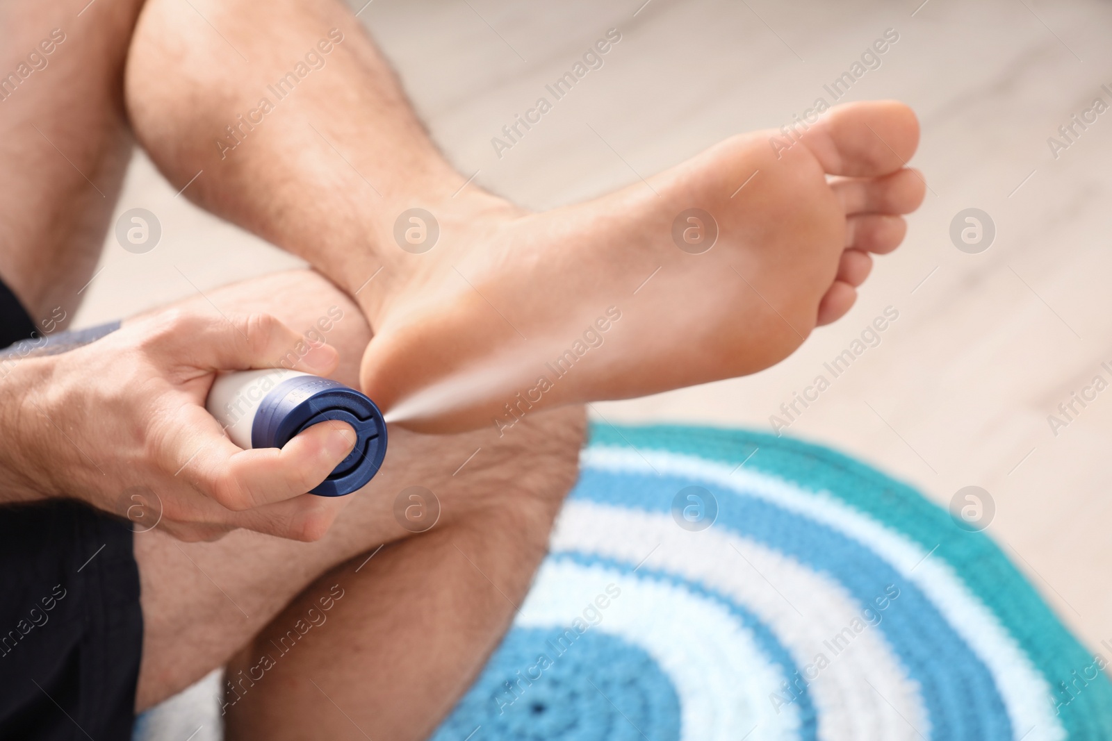 Photo of Man using foot deodorant at home, closeup view