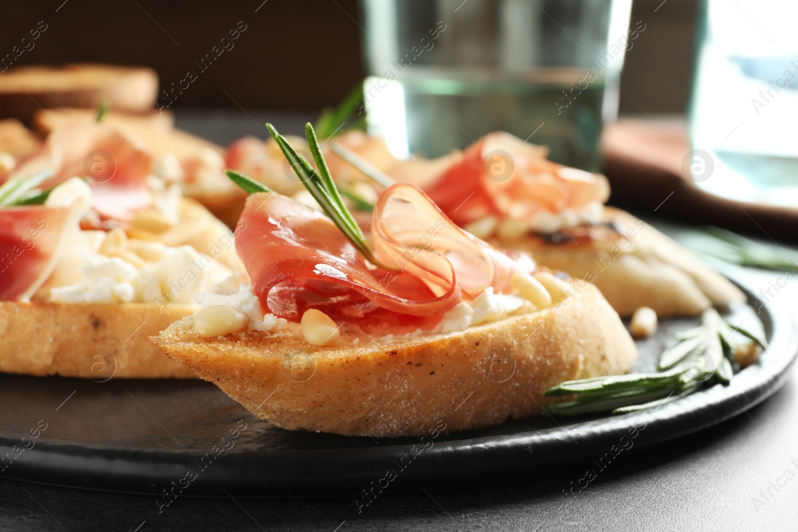 Photo of Tasty bruschettas with prosciutto and cream cheese served on table, closeup