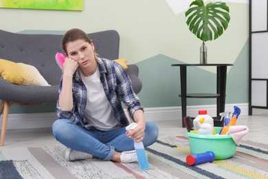 Tired woman having break while cleaning carpet with brush at home