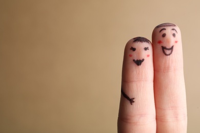 Photo of Two fingers with drawings of happy faces on brown background, space for text. Spending time together