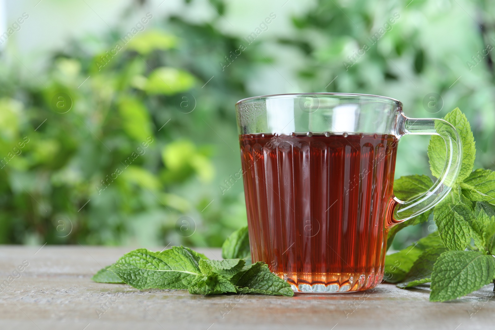 Photo of Fresh tea with mint leaves on wooden table. Space for text