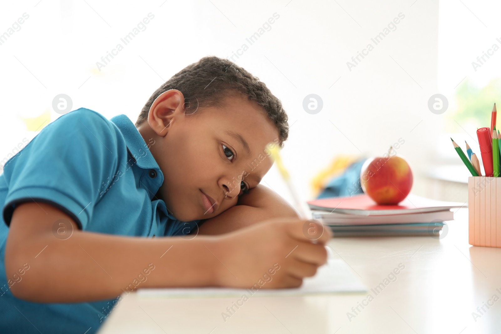 Photo of Cute little child doing assignment at desk in classroom. Elementary school