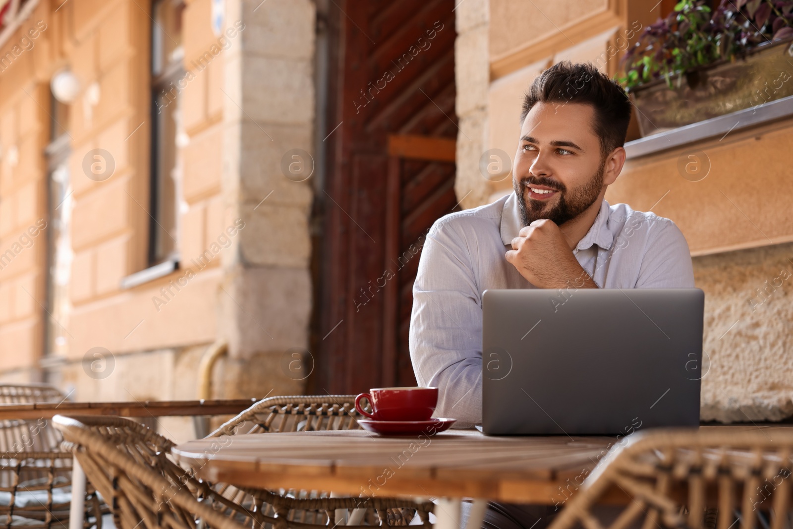 Photo of Handsome man working on laptop at table in outdoor cafe. Space for text