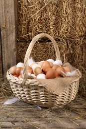 Photo of Wicker basket with fresh chicken eggs and dried straw in henhouse