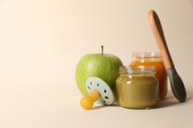 Photo of Healthy baby food, apple, pacifier and spoon on beige background. Space for text