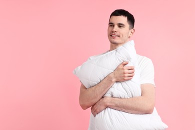 Photo of Happy man in pyjama holding pillow on pink background, space for text