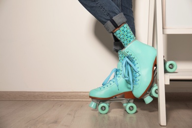 Young woman with retro roller skates against light wall, closeup. Space for text