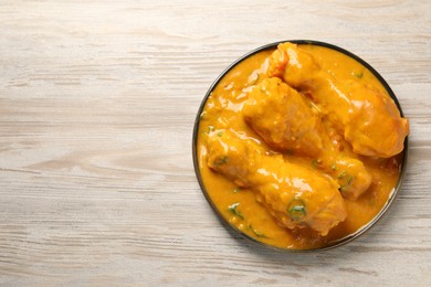 Photo of Tasty chicken curry on wooden table, top view. Space for text