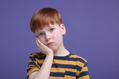 Photo of Portrait of sad little boy on purple background