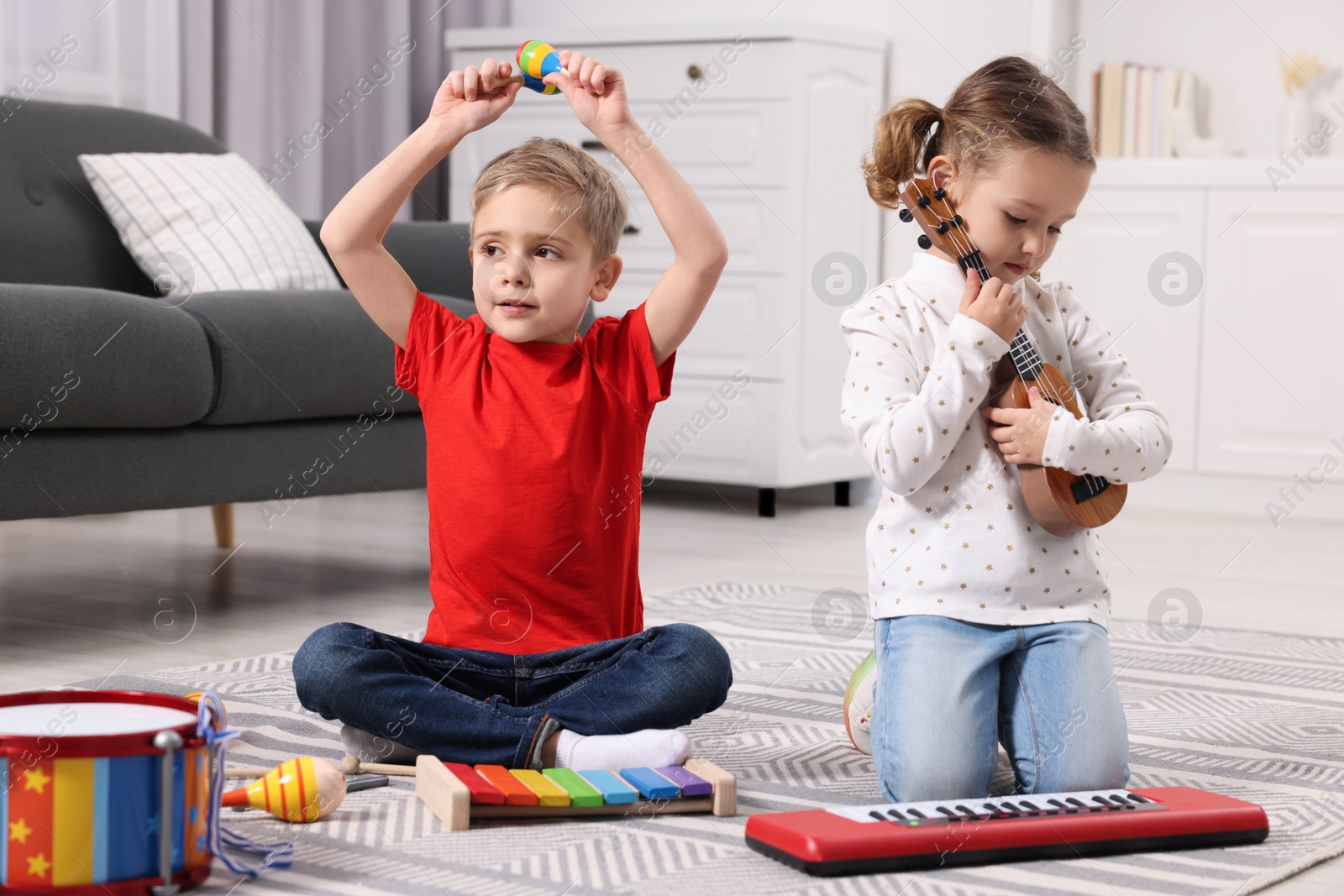 Photo of Little children playing toy musical instruments at home