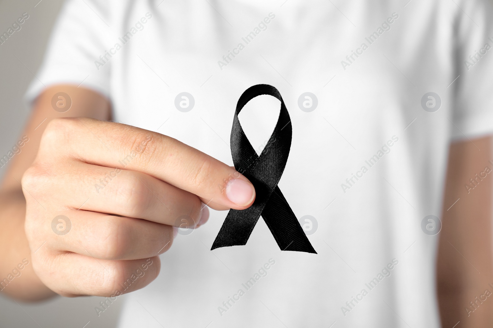 Photo of Young woman holding black ribbon, closeup. Funeral symbol