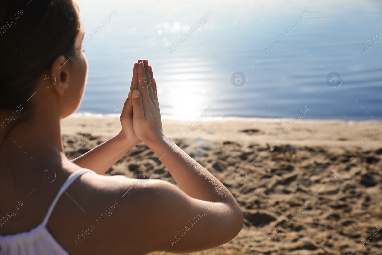 Photo of Young woman meditating near river at sunset, closeup view with space for text. Nature healing power