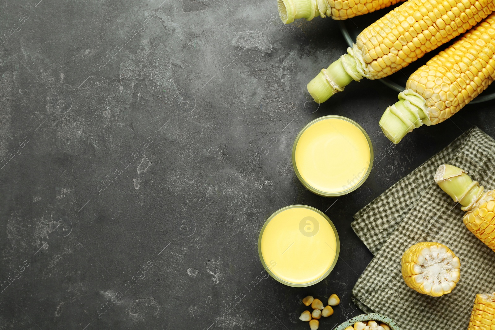 Photo of Flat lay composition with corn milk and cobs on grey table. Space for text